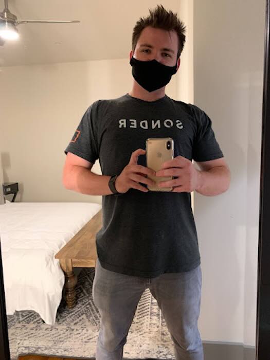 Person wearing mask taking mirror selfie in bedroom