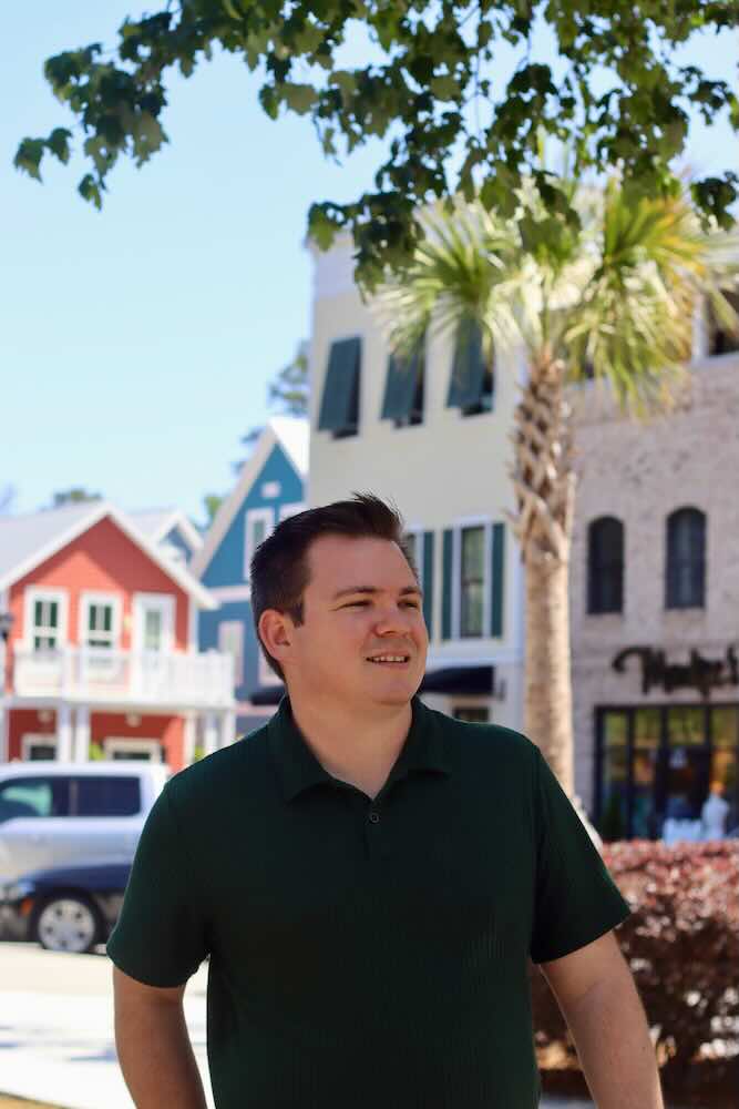 Man standing on sunny street with colorful houses