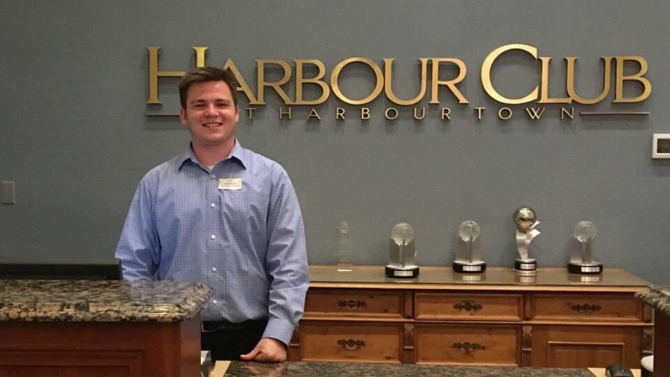 Man at Harbour Club reception desk with awards