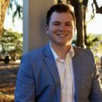 Smiling man in blazer outdoors at sunset